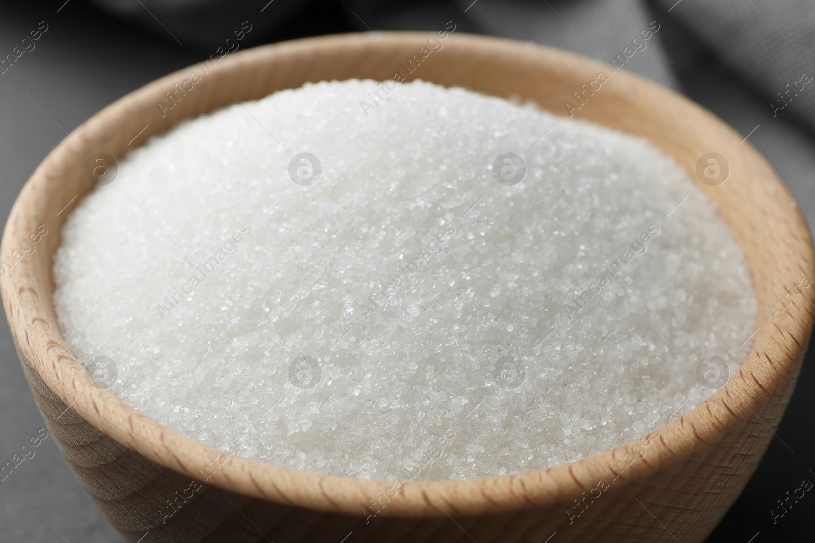 Photo of Granulated sugar in bowl on table, closeup