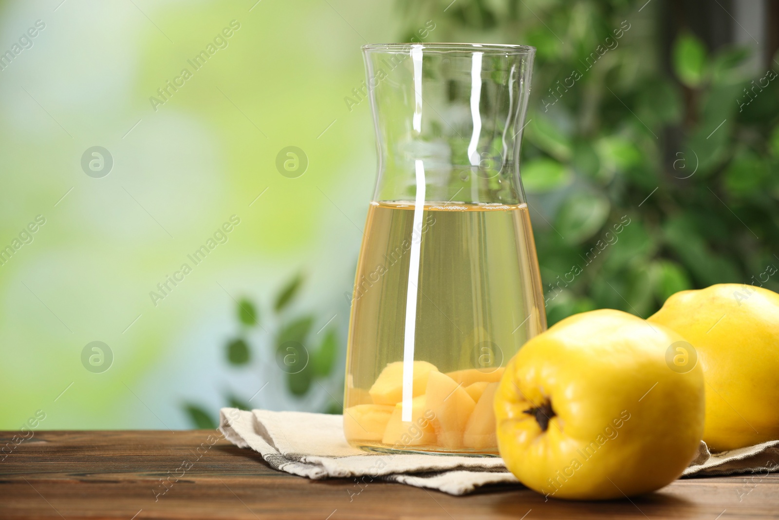 Photo of Delicious quince drink and fresh fruits on wooden table against blurred background. Space for text