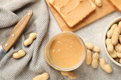 Photo of Tasty peanut butter sandwich and peanuts on gray table, flat lay
