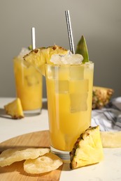 Tasty pineapple cocktail with ice cubes and delicious fruit on white table