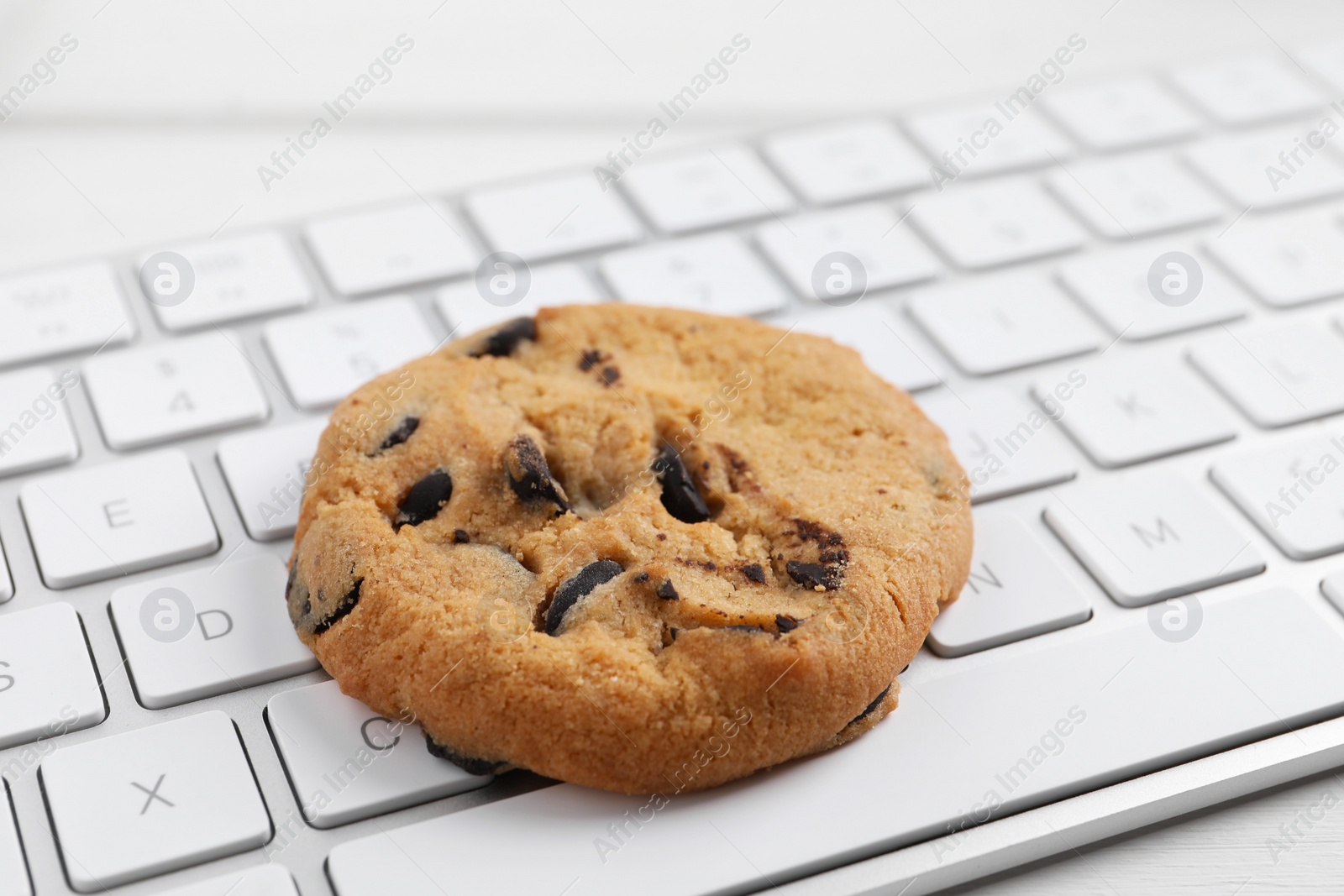 Photo of Chocolate chip cookie on keyboard, closeup view