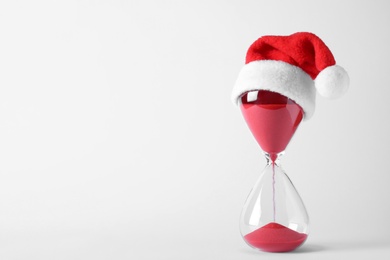 Photo of Hourglass with Santa hat isolated on white. Christmas countdown