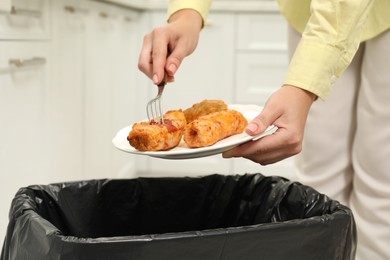 Photo of Woman throwing cabbage rolls into bin indoors, closeup