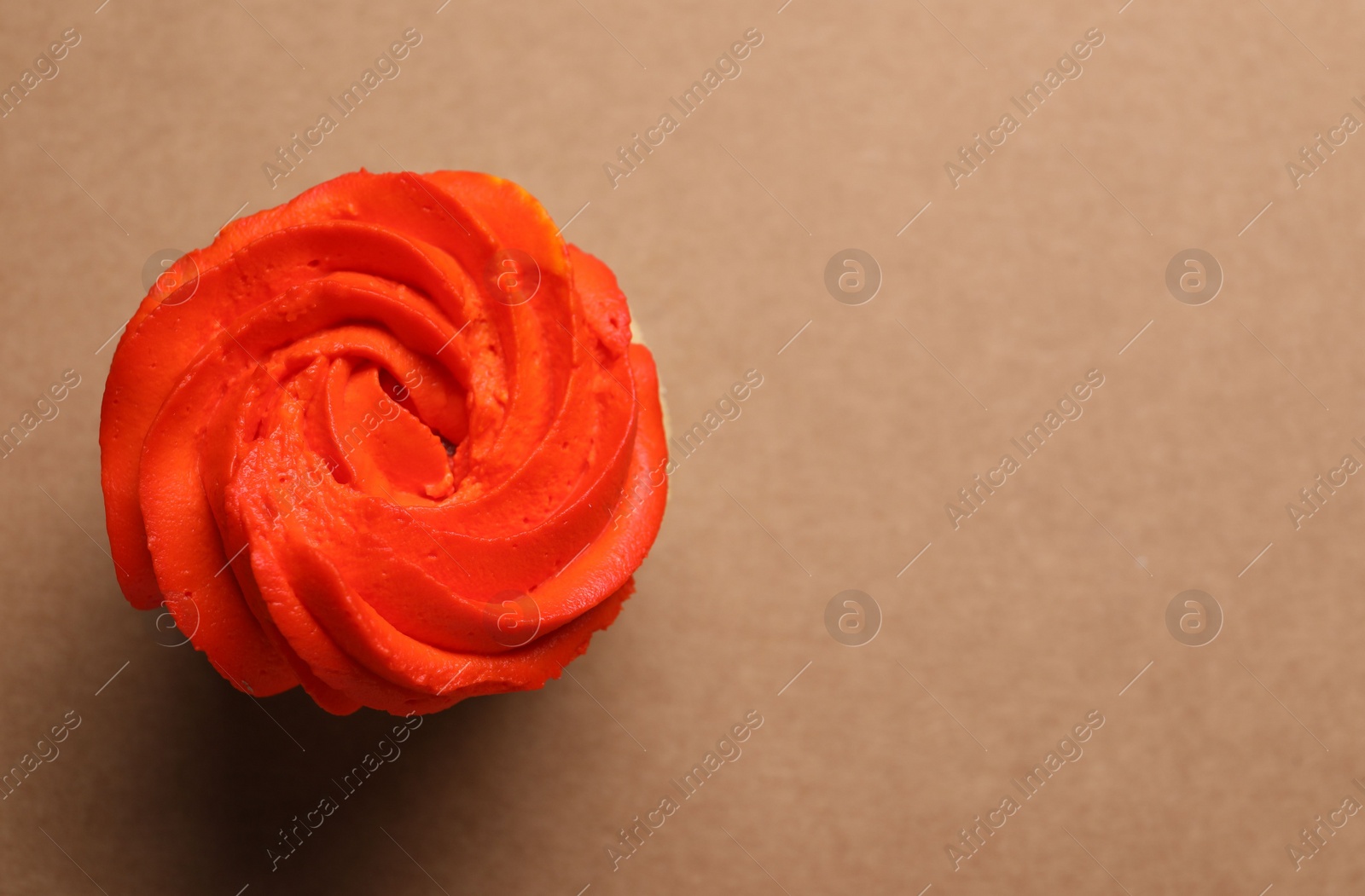 Photo of Delicious cupcake with bright cream on brown background, top view. Space for text