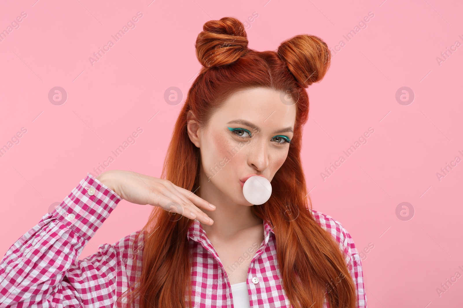 Photo of Portrait of beautiful woman with bright makeup blowing bubble gum on pink background