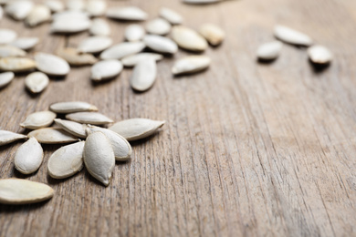 Closeup view of raw pumpkin seeds on wooden background, space for text. Vegetable planting