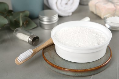 Tooth powder and brush on grey table, closeup