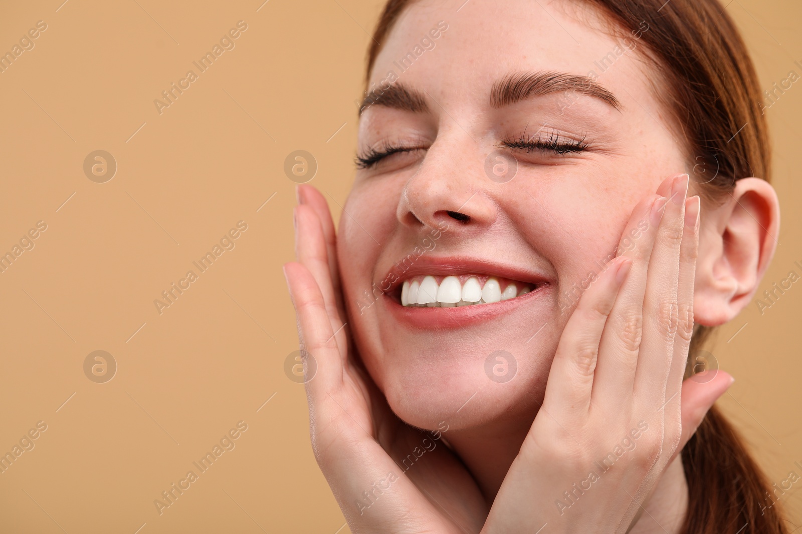 Photo of Portrait of smiling woman with freckles on beige background, closeup. Space for text