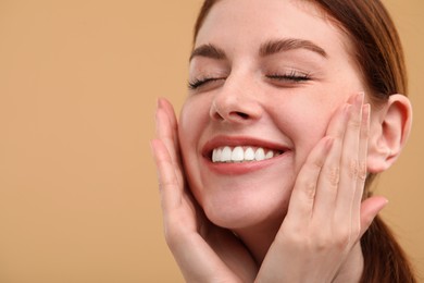 Portrait of smiling woman with freckles on beige background, closeup. Space for text