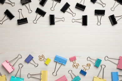 Binder clips on white wooden background, flat lay. Space for text