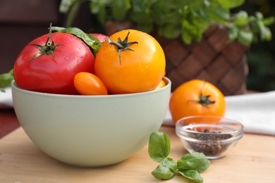 Photo of Different sorts of tomatoes, and basil on wooden table