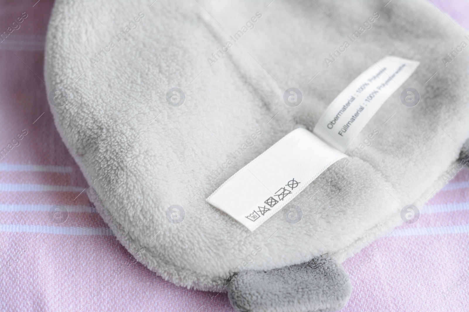 Photo of White clothing label with care information on light gray garment