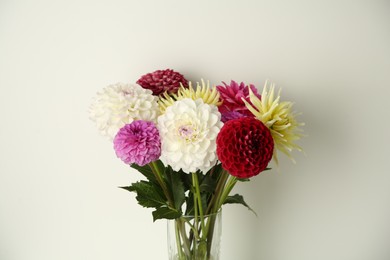 Photo of Bouquet of beautiful Dahlia flowers in vase near white wall