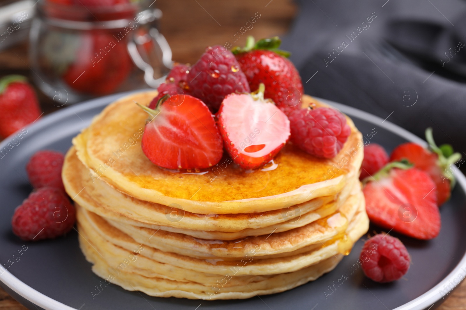 Photo of Tasty pancakes with fresh berries and honey on plate, closeup