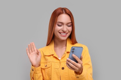 Photo of Beautiful happy woman having video chat via smartphone on grey background