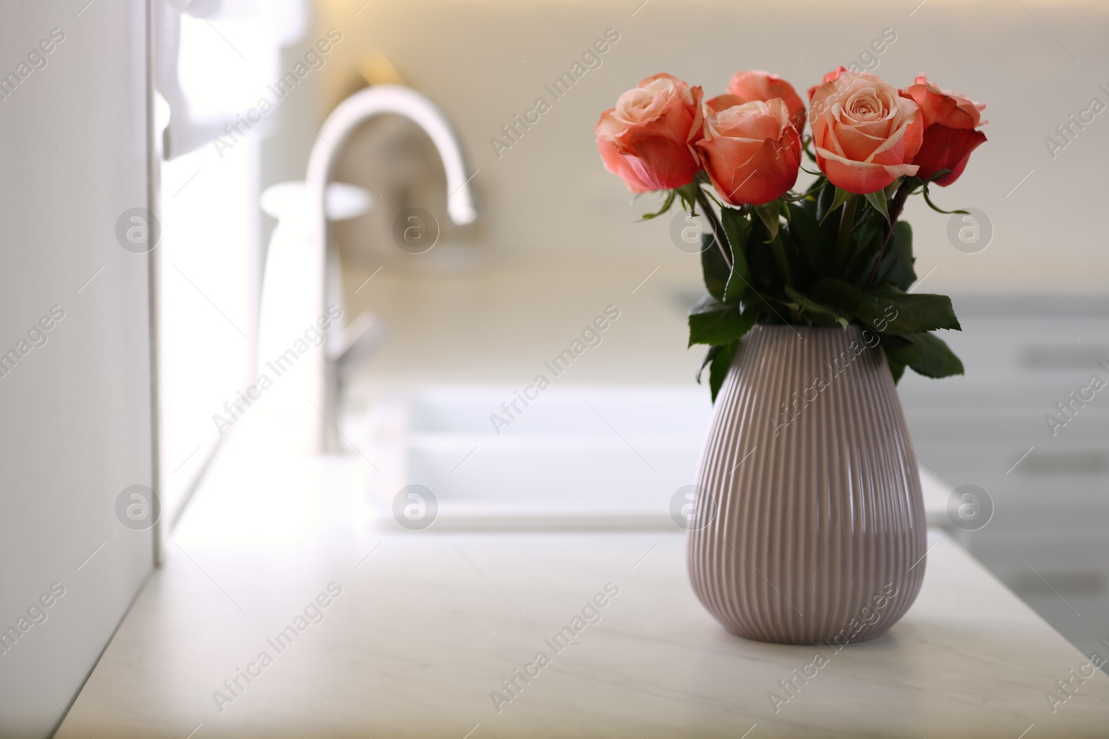 Photo of Vase with beautiful roses on countertop in kitchen, space for text. Interior design