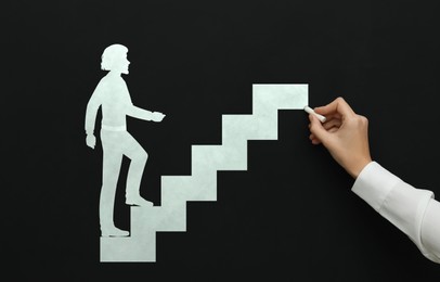 Image of Woman drawing person going up stairs on chalkboard, closeup. Steps to success