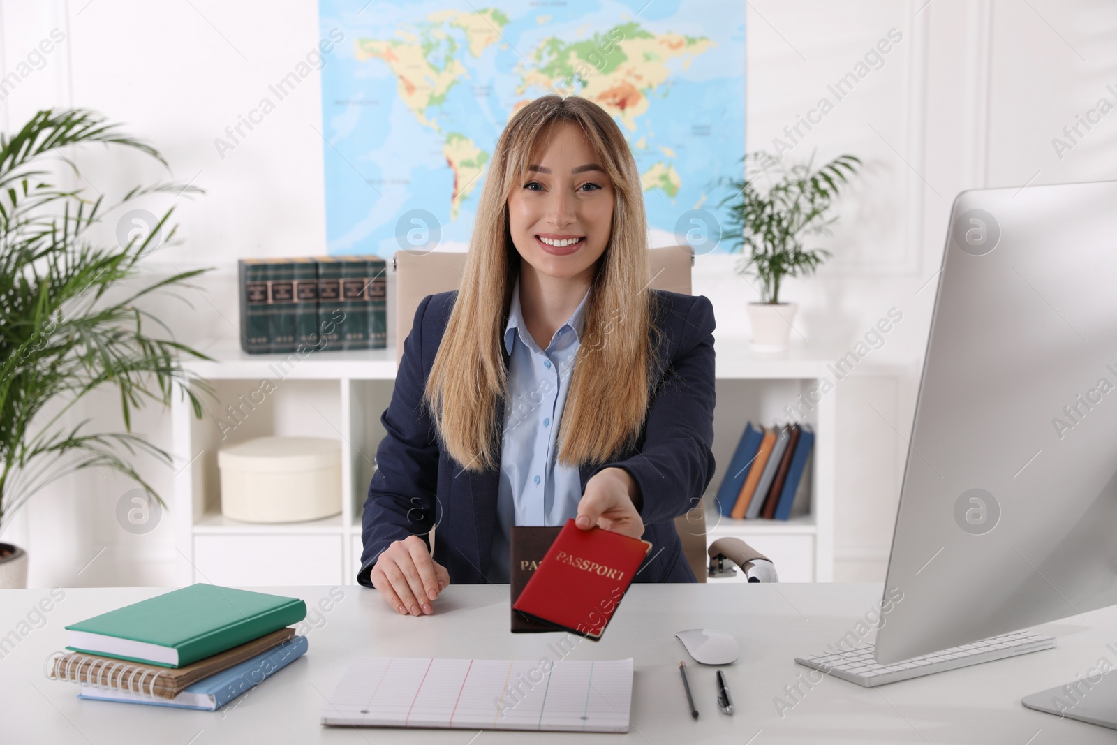 Photo of Happy manager holding passports at desk in travel agency