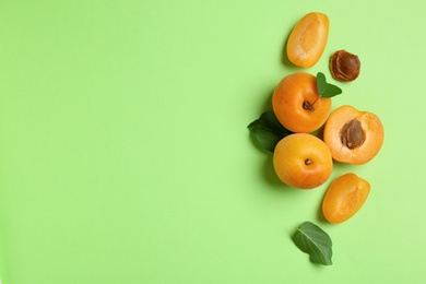 Photo of Delicious ripe sweet apricots on green background, flat lay. Space for text