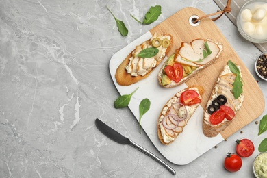 Photo of Board with delicious chicken bruschettas on grey marble table, flat lay. Space for text