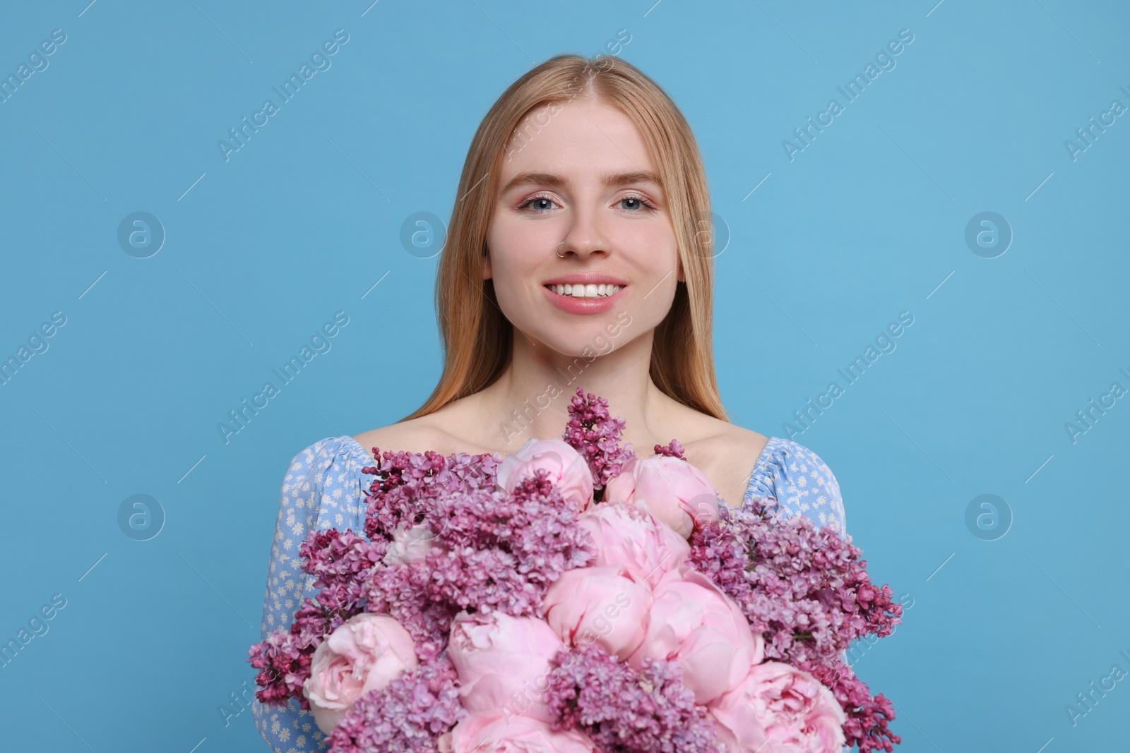 Photo of Beautiful woman with bouquet of spring flowers on light blue background