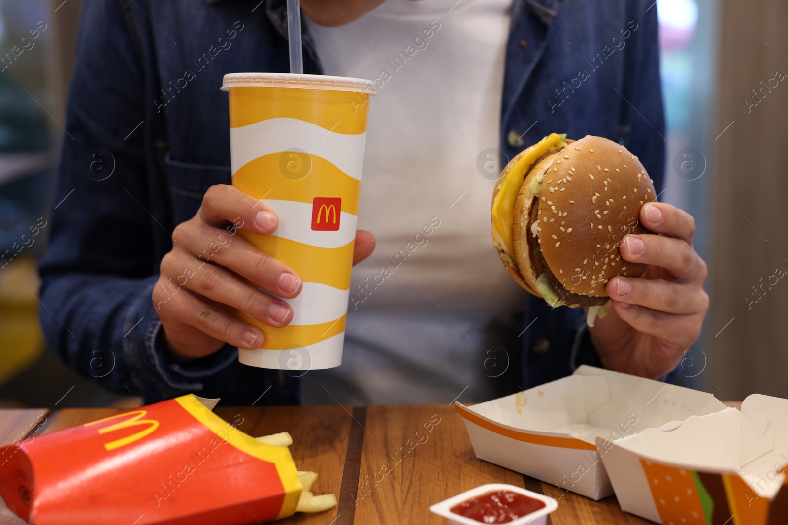 Photo of Lviv, Ukraine - October 9, 2023: Woman with McDonald's menu at wooden table in restaurant, closeup