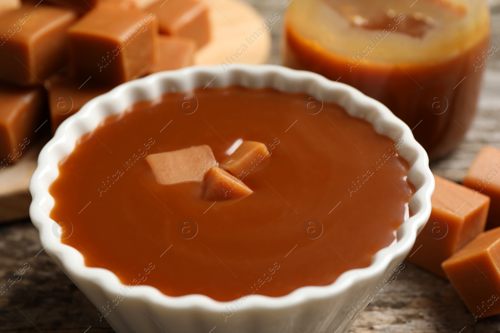 Photo of Tasty salted caramel with candies on table, closeup