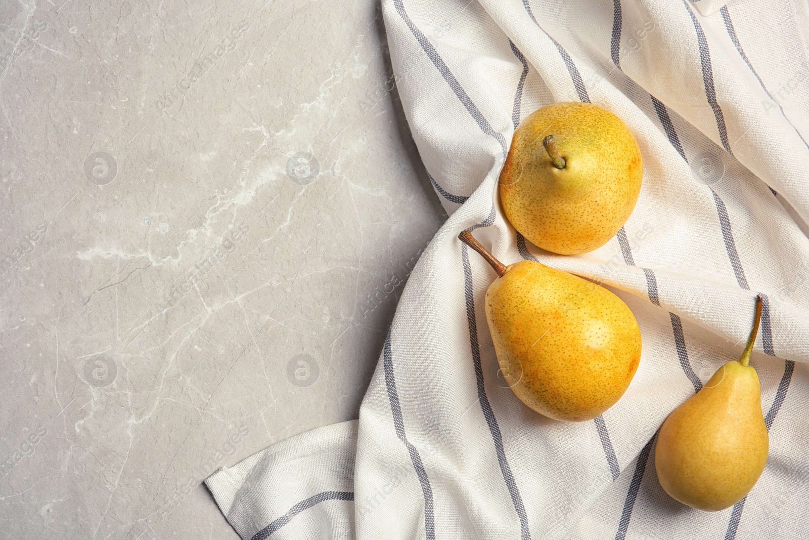 Photo of Ripe pears and striped fabric on grey background, top view. Space for text