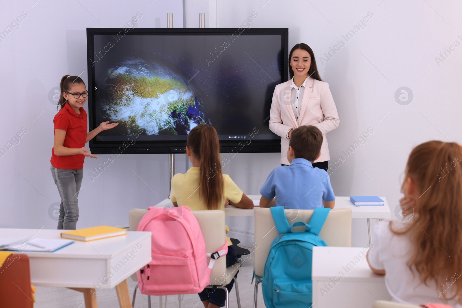 Photo of Teacher and pupil using interactive board in classroom during lesson