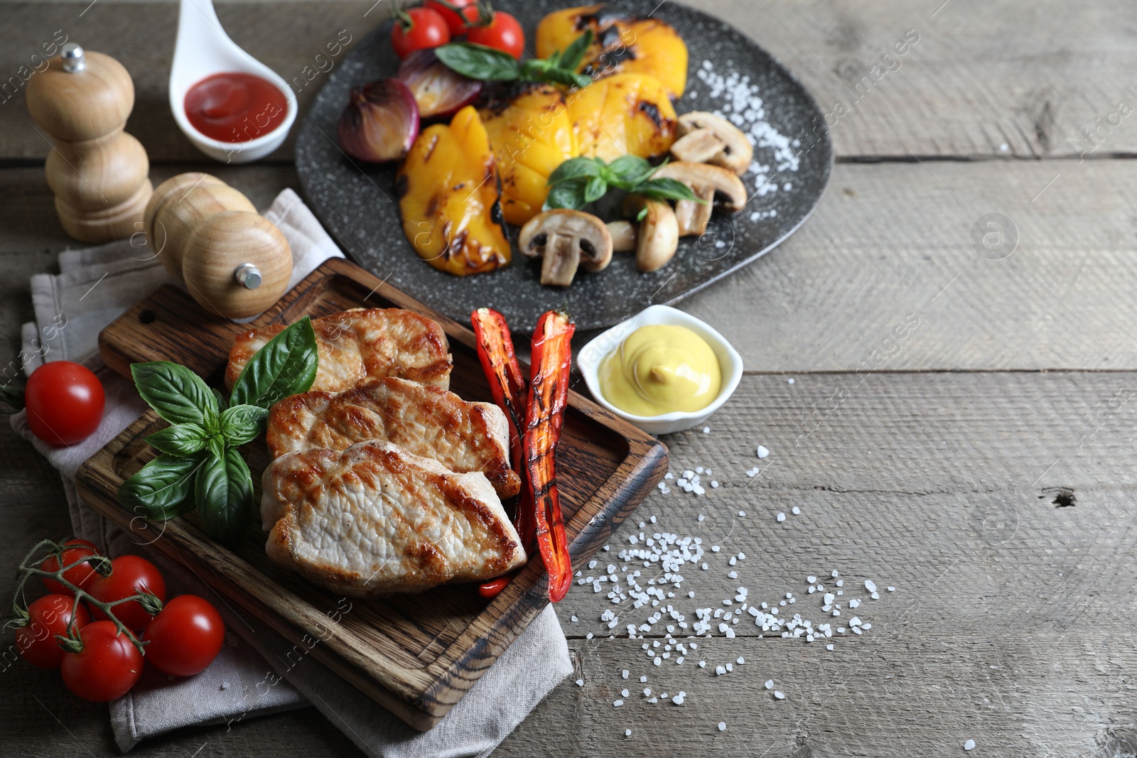 Photo of Delicious grilled meat and vegetables served on wooden table. Space for text