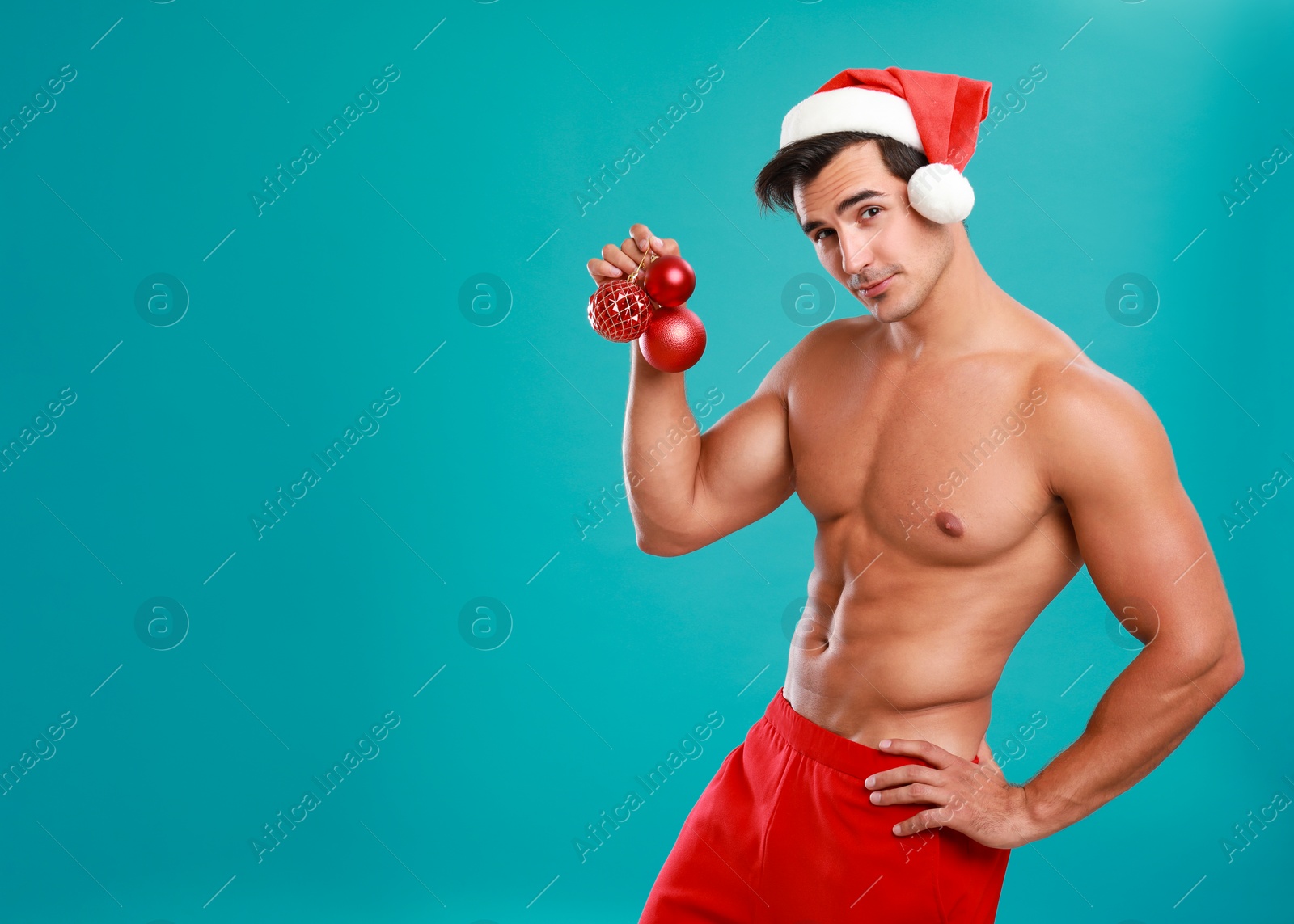 Photo of Sexy shirtless Santa Claus with Christmas balls on blue background, space for text