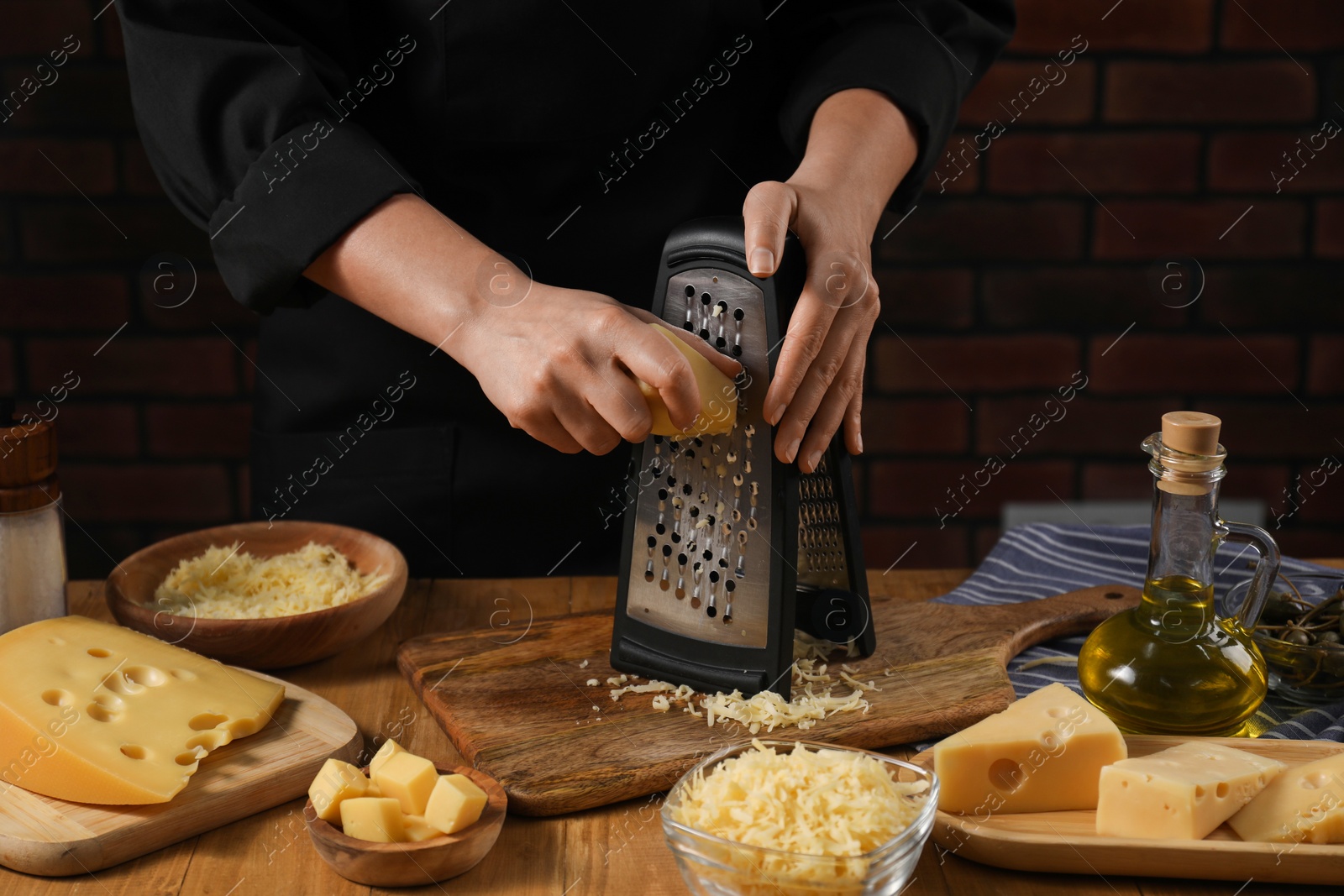 Photo of Woman grating cheese at wooden table, closeup