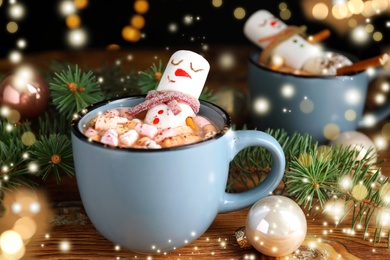 Image of Marshmallow snowman in cup with hot drink on wooden table. Bokeh effect 