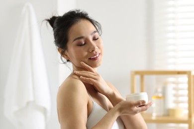 Happy woman applying body cream at home