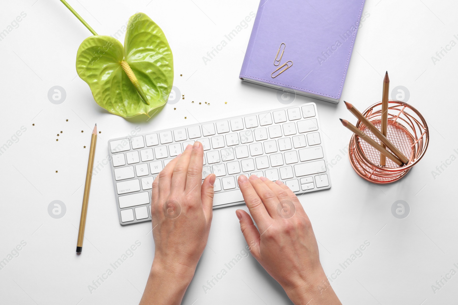 Photo of Woman using computer keyboard on white table decorated with tropical flower, top view. Creative design ideas