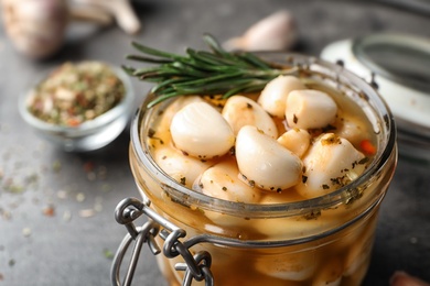 Preserved garlic in glass jar on table, closeup