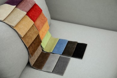 Photo of Catalog of colorful fabric samples on grey sofa