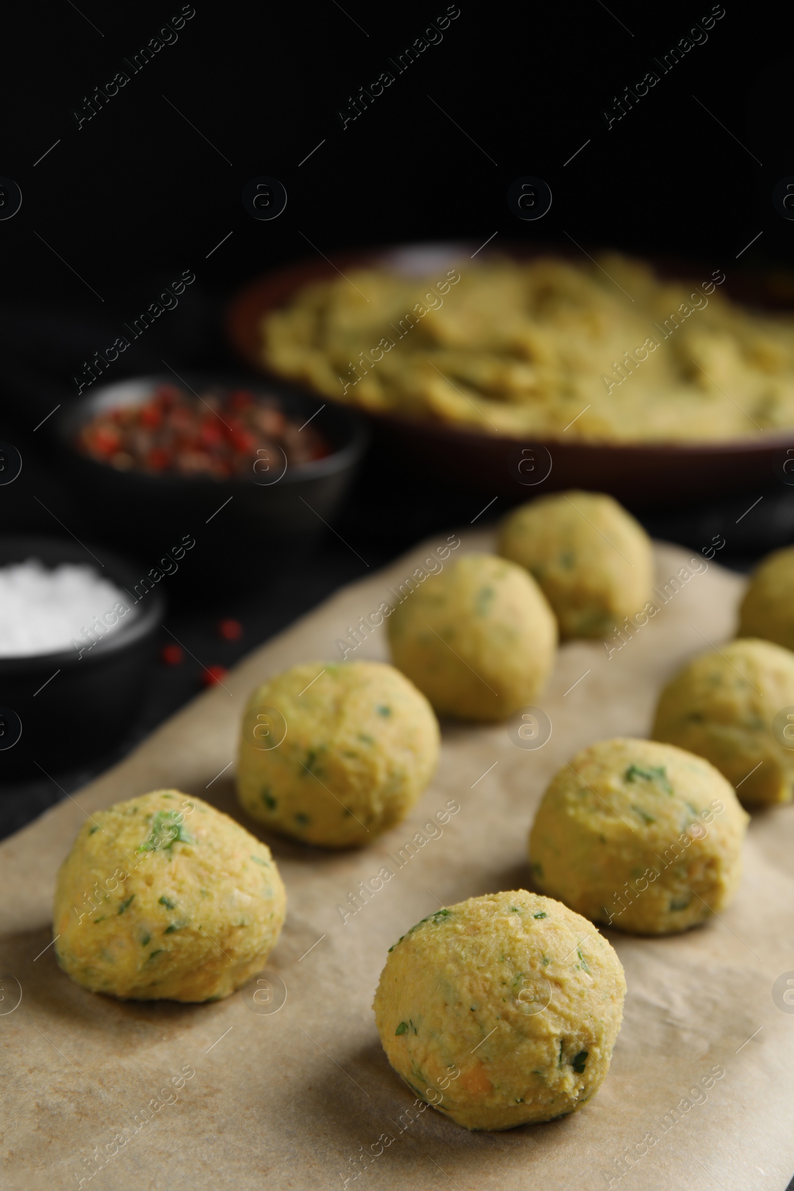 Photo of Raw falafel balls on black table. Space for text