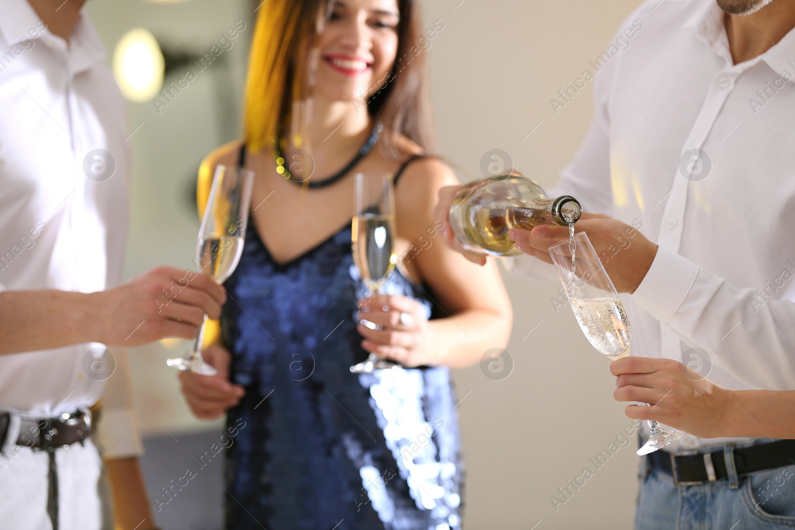 Photo of Man pouring friends champagne at festive party indoors