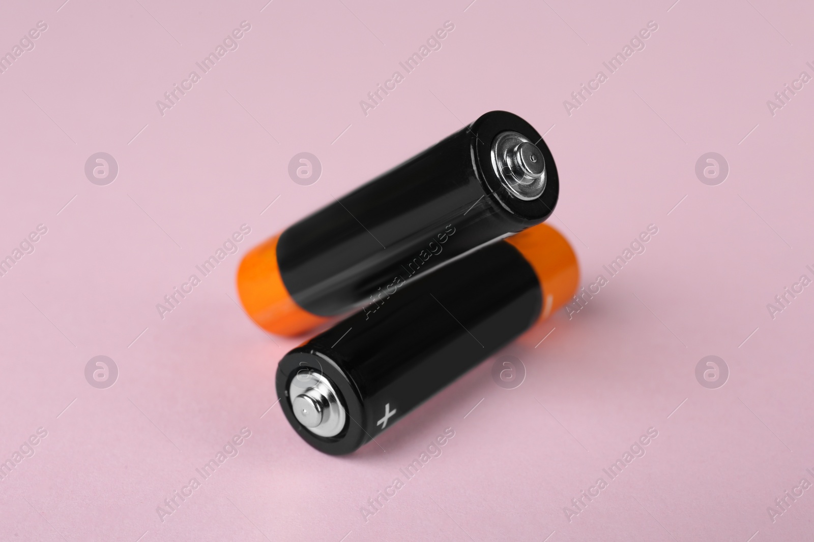 Image of New AA batteries on pink background, closeup