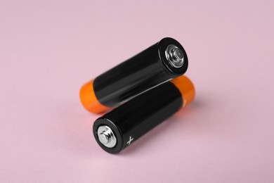 New AA batteries on pink background, closeup