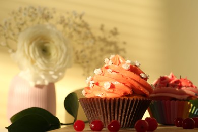 Delicious cupcake with bright cream and flowers on wooden table