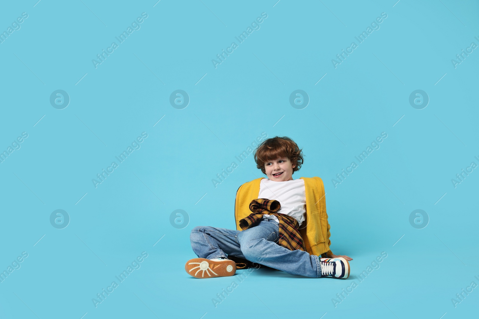 Photo of Happy little boy dancing on light blue background. Space for text