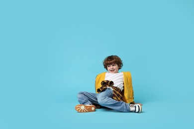 Photo of Happy little boy dancing on light blue background. Space for text