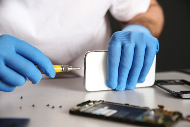 Photo of Technician repairing mobile phone at table, closeup