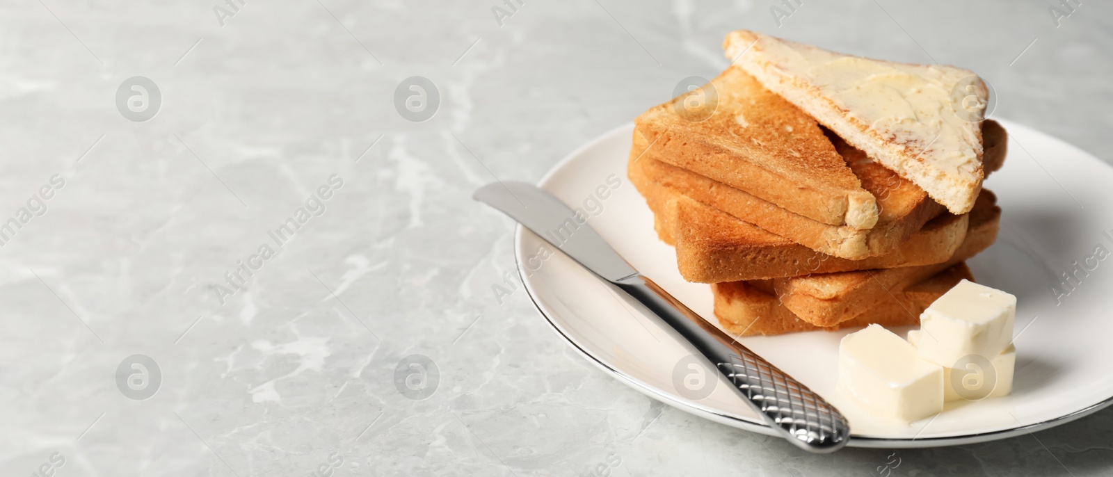 Image of Tasty toasts with butter served on grey marble table, space for text. Banner design