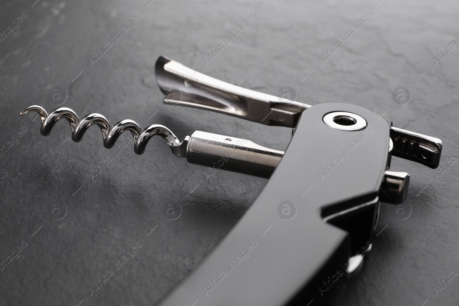 Photo of One corkscrew (sommelier knife) on grey textured table, closeup