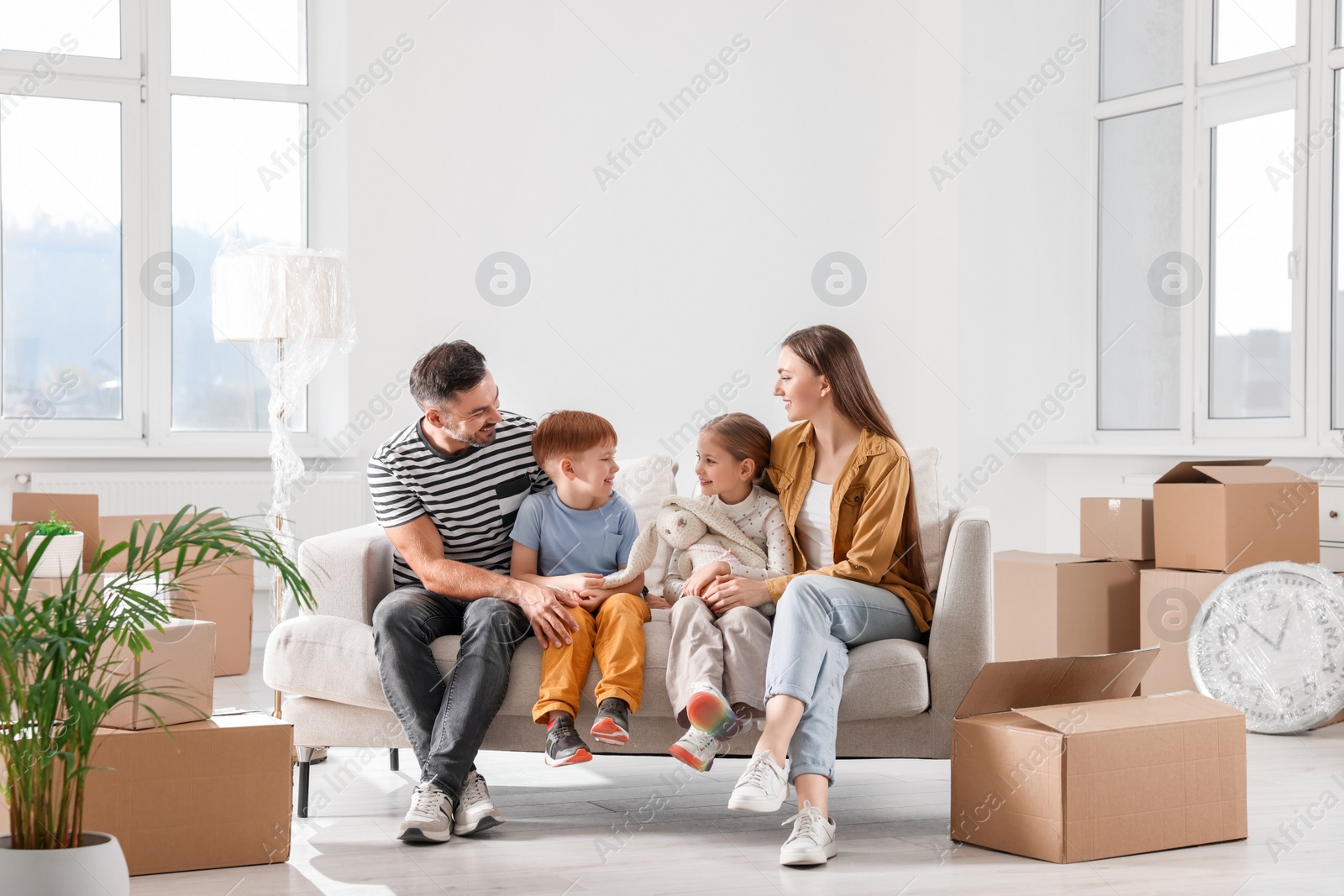 Photo of Happy family sitting on couch in new apartment. Moving day