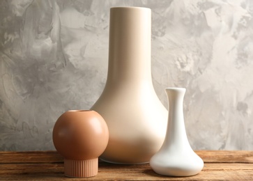 Photo of Stylish empty ceramic vases on wooden table against grey background
