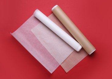 Rolls of baking paper on red background, top view